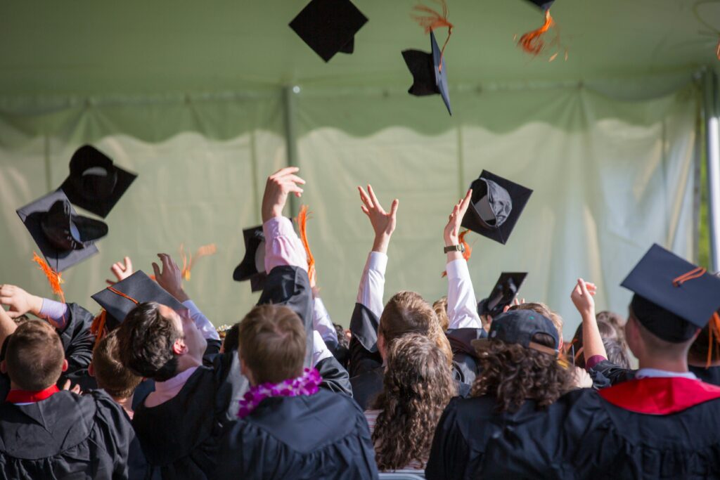 Group of graduates in caps and gowns celebrating by tossing their caps into the air, symbolizing achievement and academic success