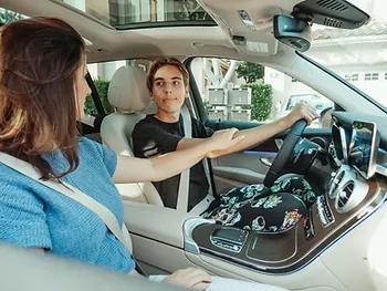 Teenager driving a car with an adult passenger offering guidance, highlighting the importance of safe driving habits and tips to reduce teenage driver insurance costs