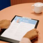 Close-up of hands holding resume during interview with coffee on table, highlighting workplace setting.